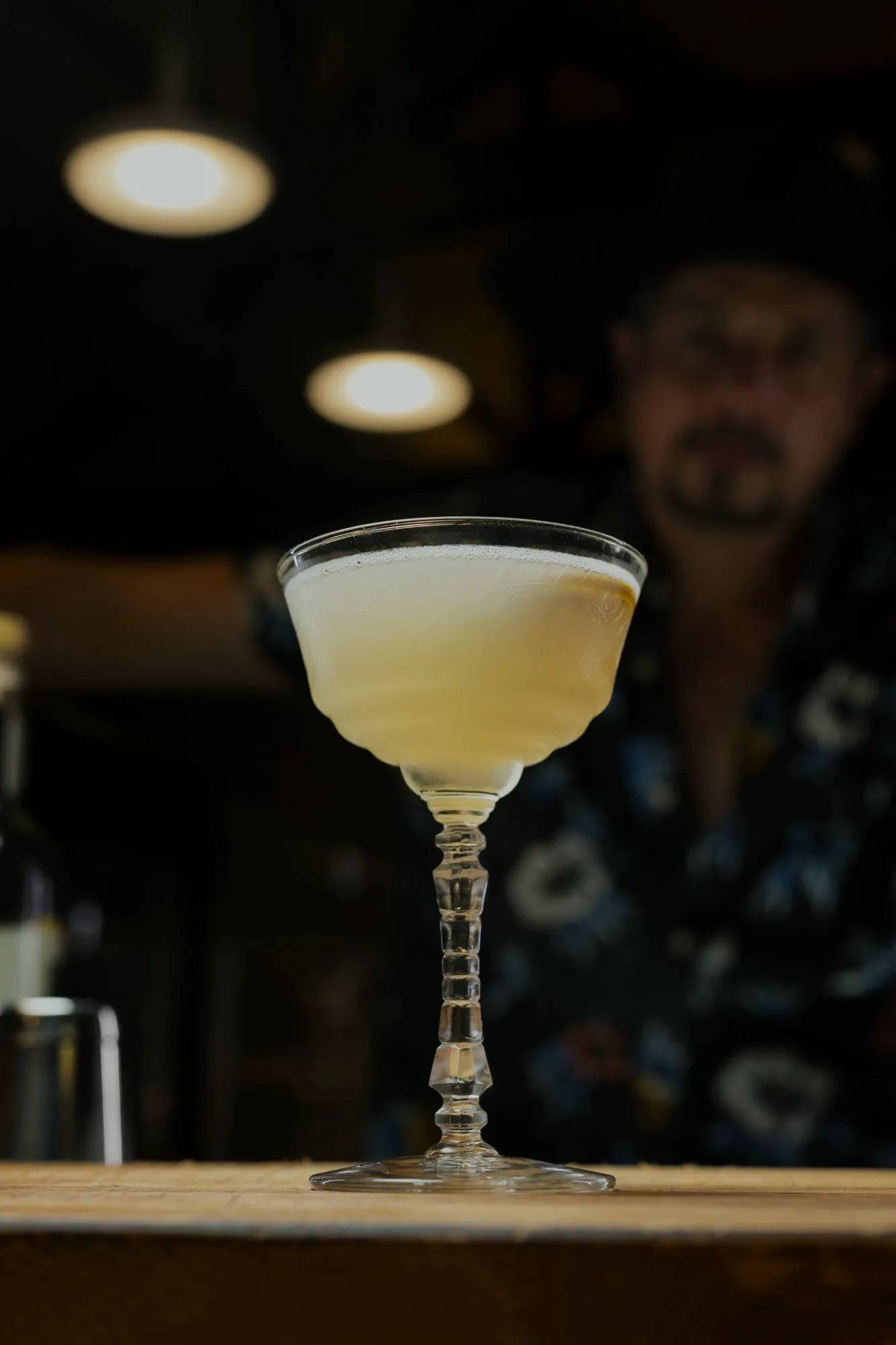 Bartender straining a craft cocktail into a coupe at Adesso